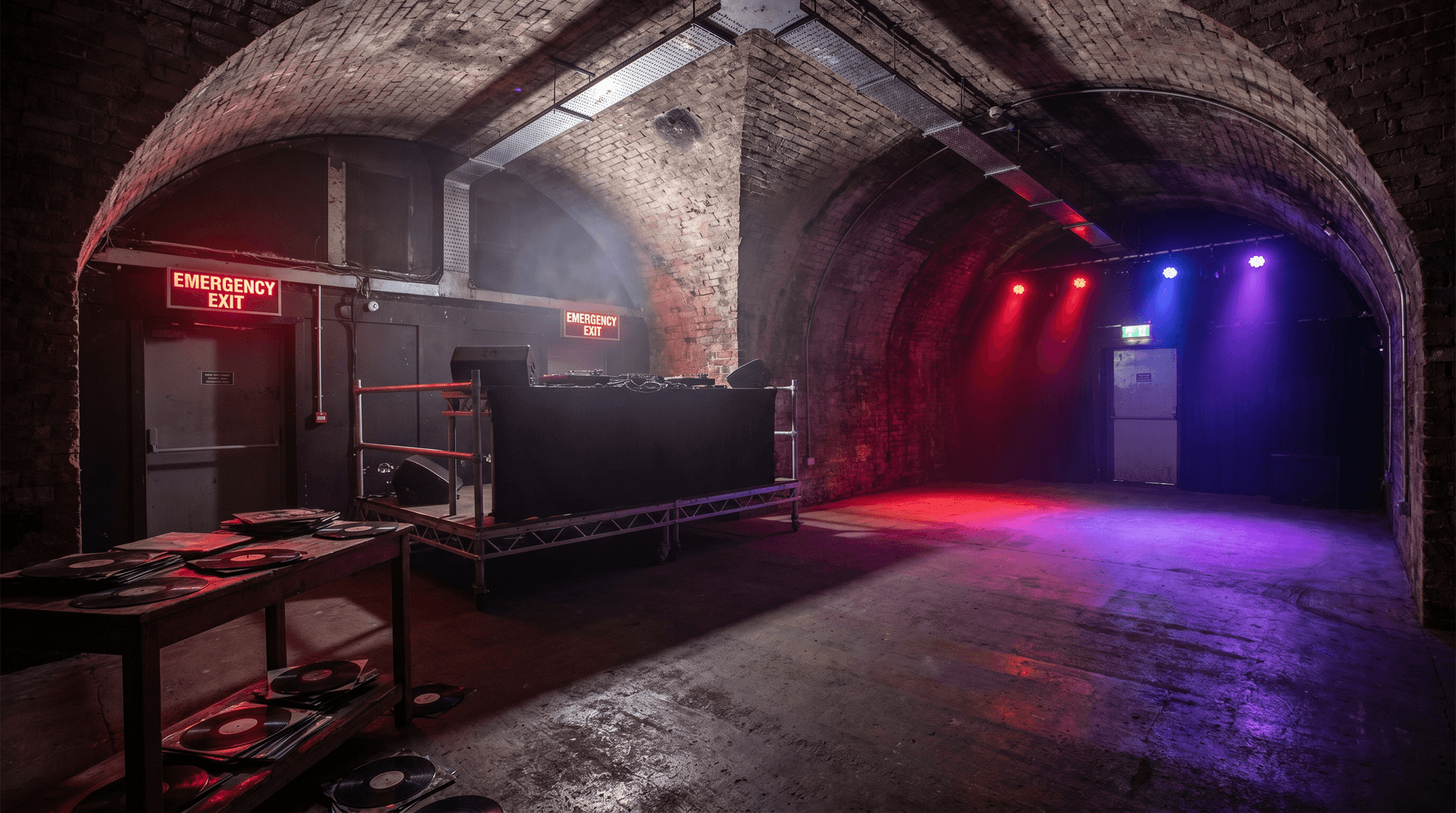 Dark underground club venue with concrete arches and professional sound system