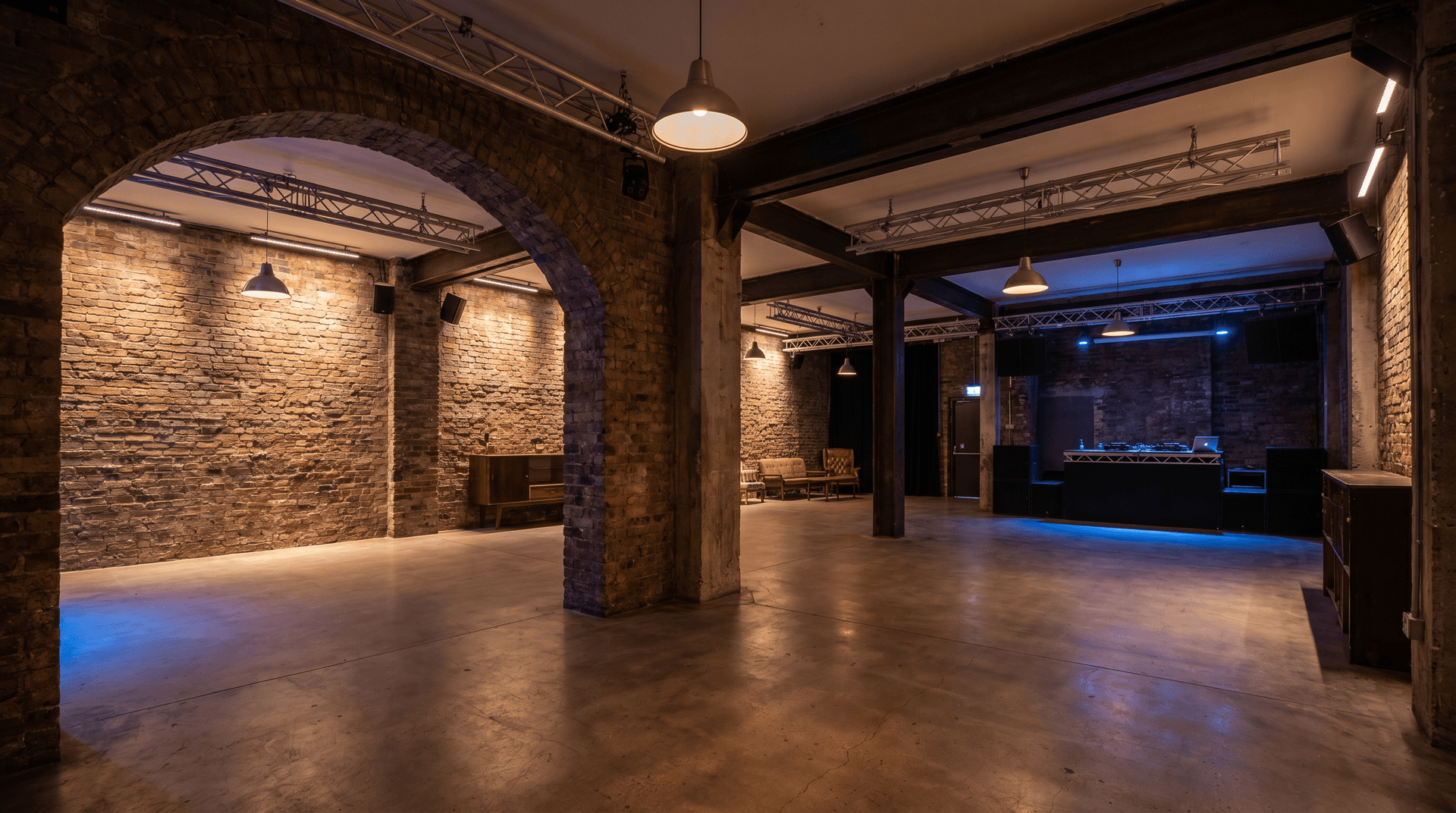 Empty nightclub interior with dual-room layout, exposed brick walls, and industrial lighting fixtures