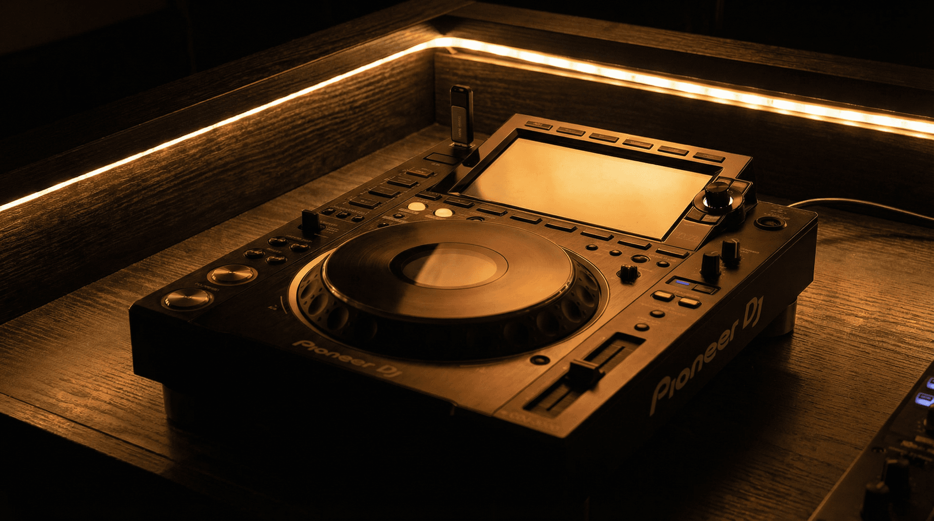 Pioneer DJ media player with USB drive on a DJ booth under warm amber lighting