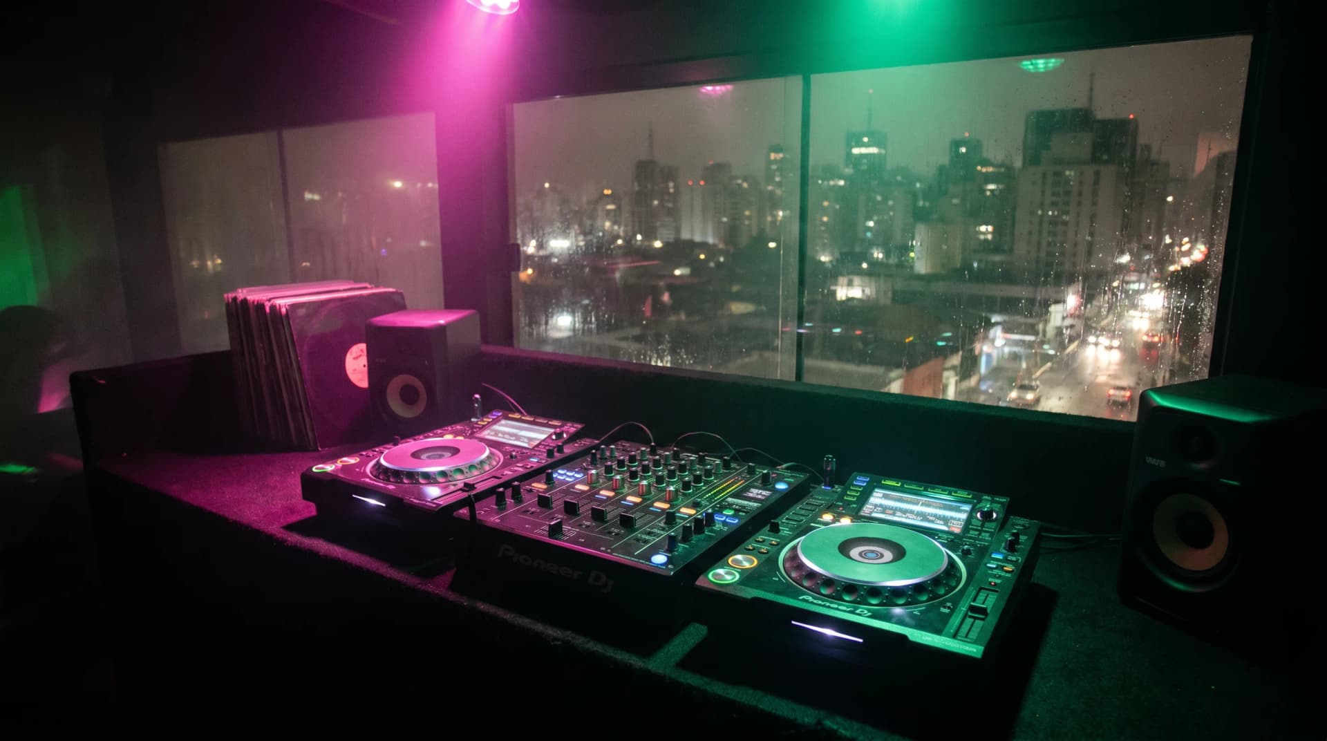 DJ booth setup with mixer and turntables against vibrant pink and green lighting representing Brazilian baile funk culture