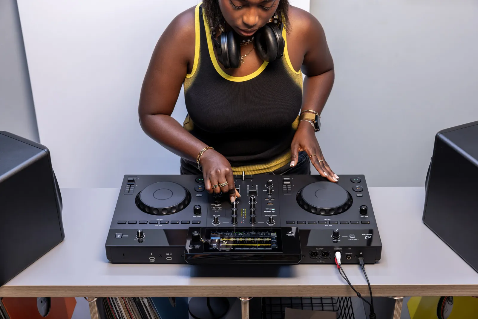 A DJ playing an AlphaTheta XDJ-AN at home between two monitor speakers