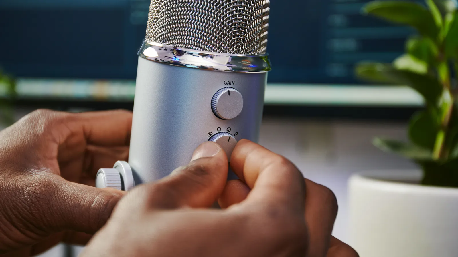 A hand turning the pattern knob on a silver Logitech Yeti
