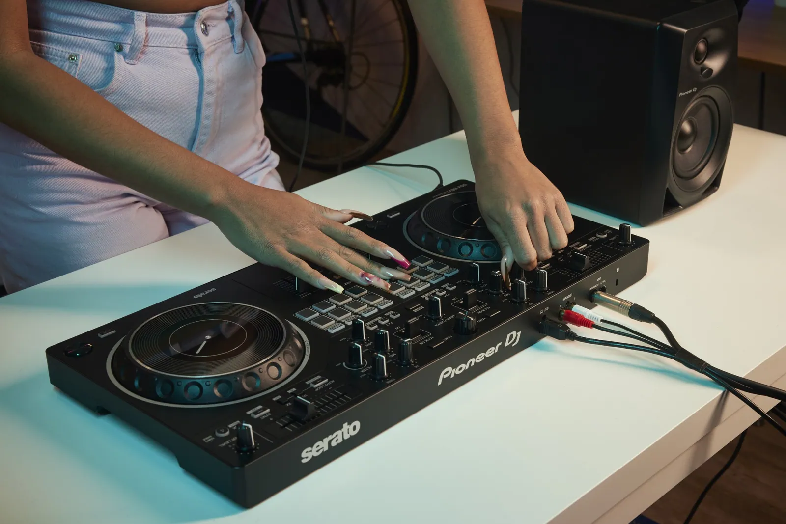 Hands on a Pioneer DJ DDJ-REV1 on a desk
