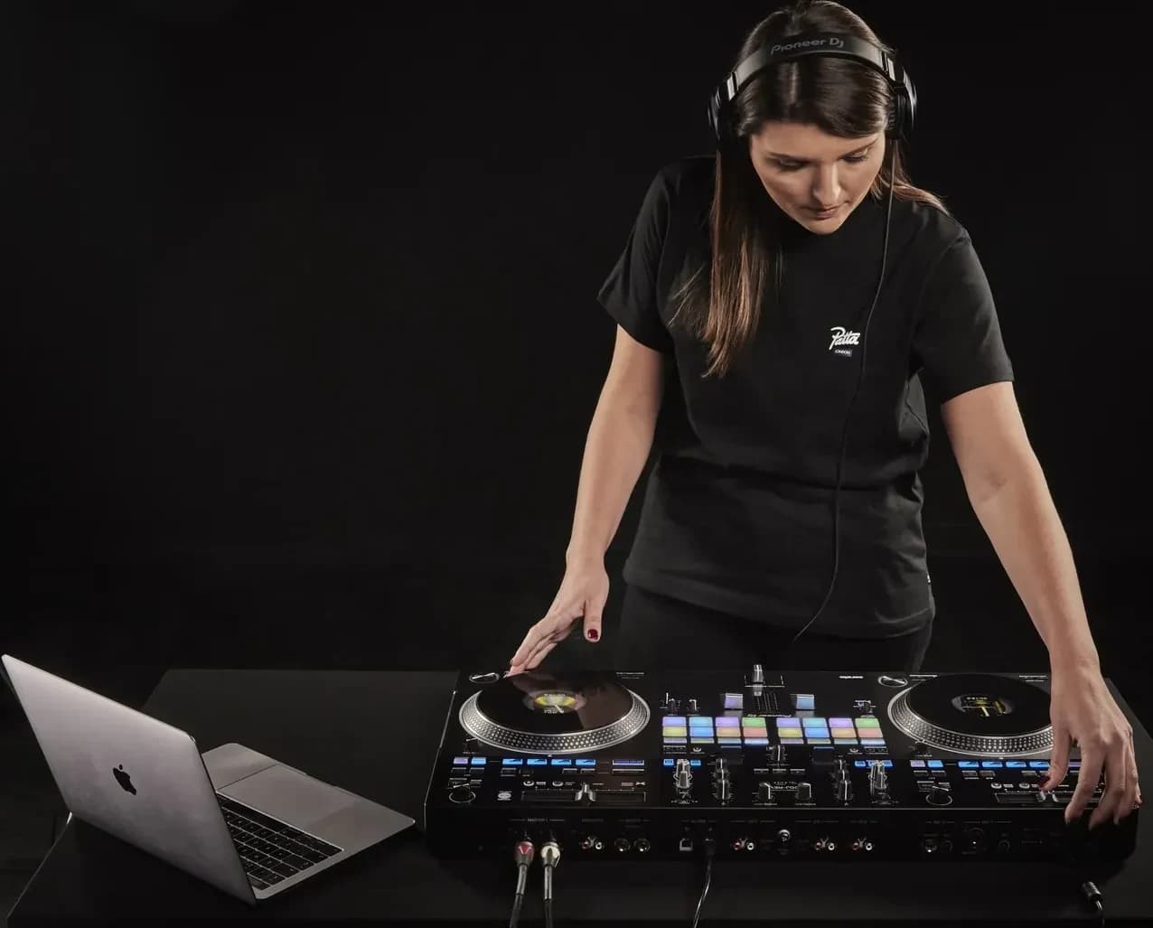 A DJ playing a Pioneer DJ DDJ-REV7 with a laptop