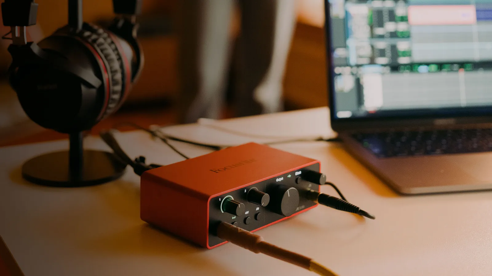 A Focusrite Scarlett Solo (4th Gen) on a desk beside headphones and a laptop