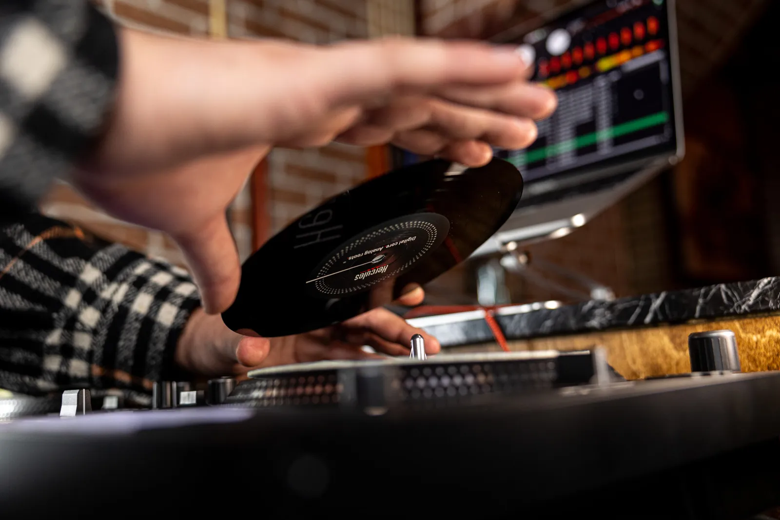 A DJ placing a 7-inch record on the platter of a Hercules DJControl Inpulse T7