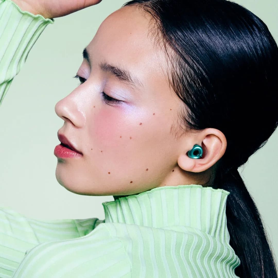 A woman wearing a Loop Switch 2 earplug in Emerald