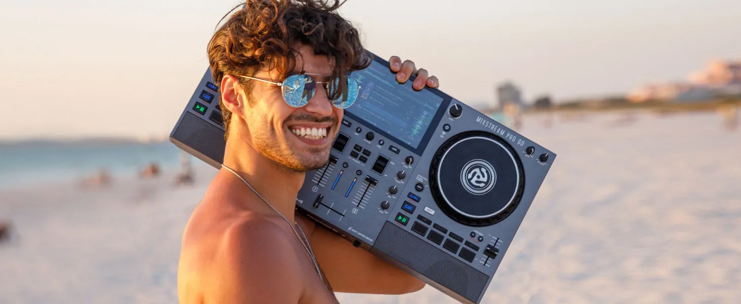 A person carrying a Numark Mixstream Pro Go on a beach