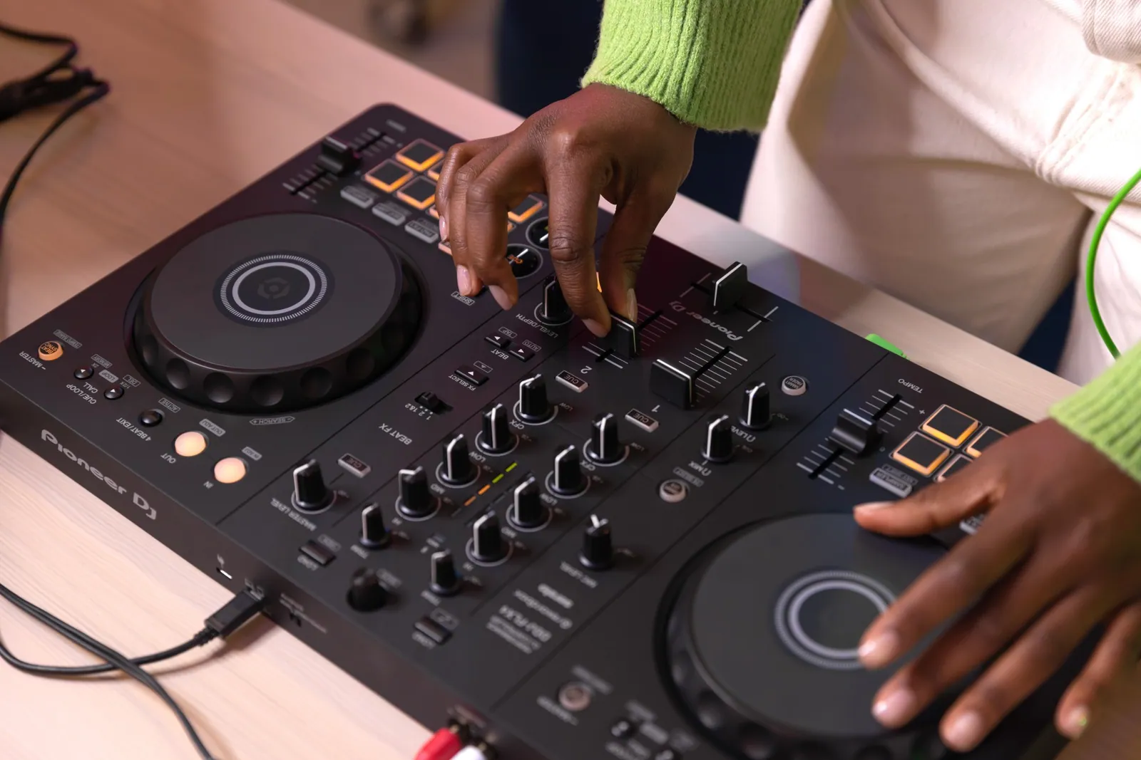 Hands on the mixer section of a Pioneer DJ DDJ-FLX4