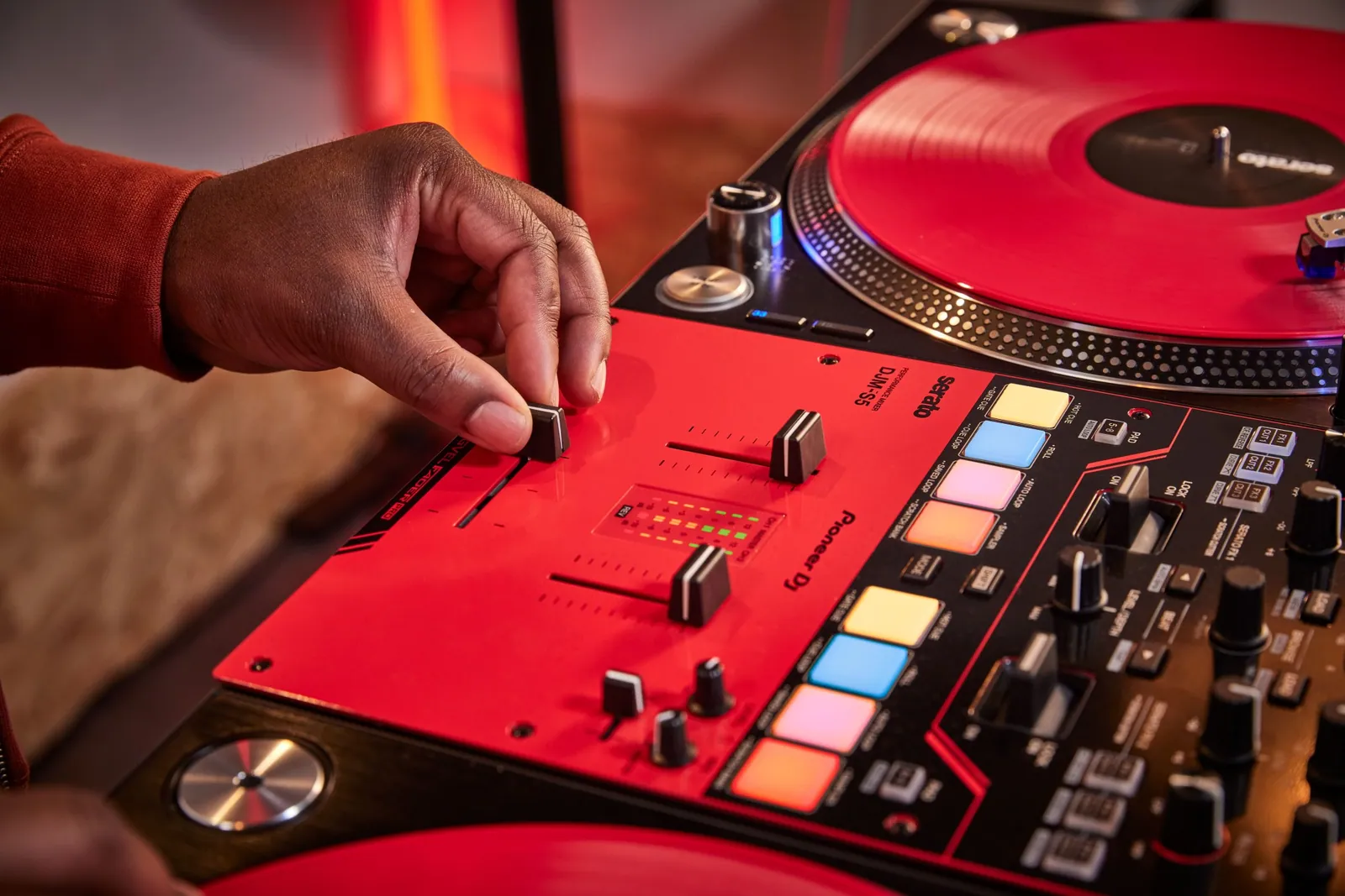 A DJ's hands on the crossfader and pads of a Pioneer DJ DJM-S5