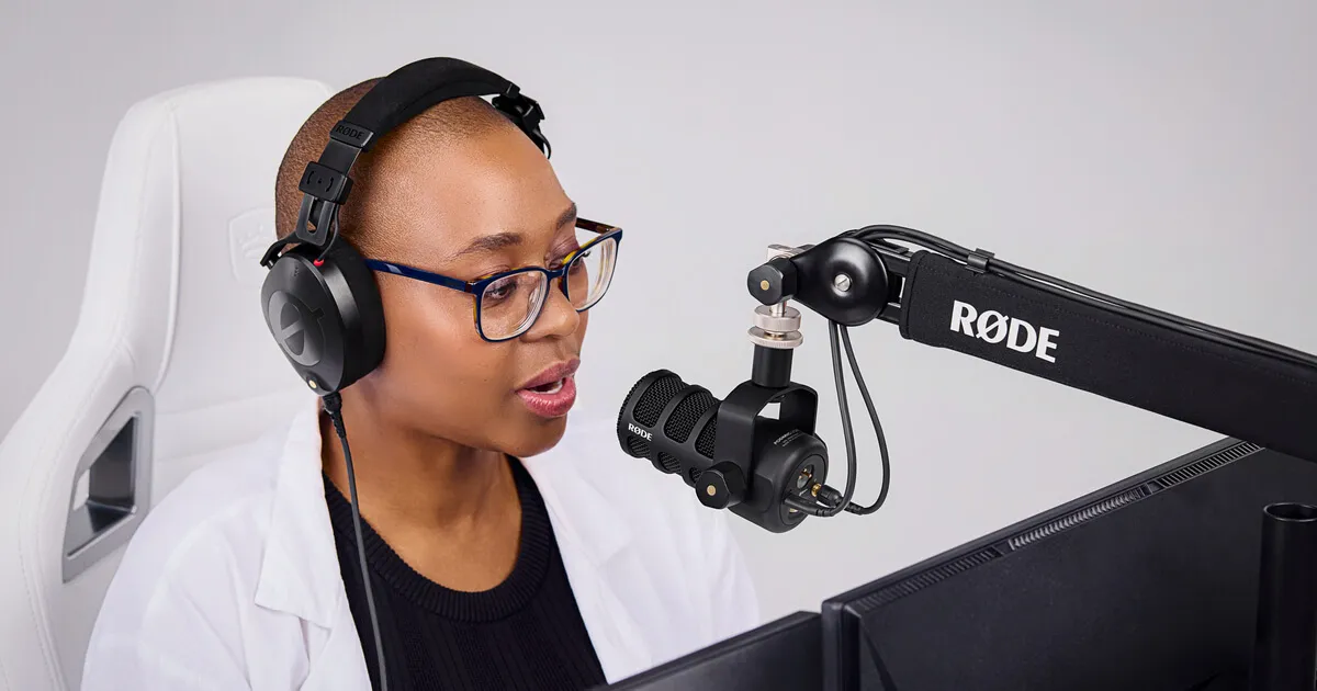 A podcaster speaking into a RØDE PodMic USB on a boom arm