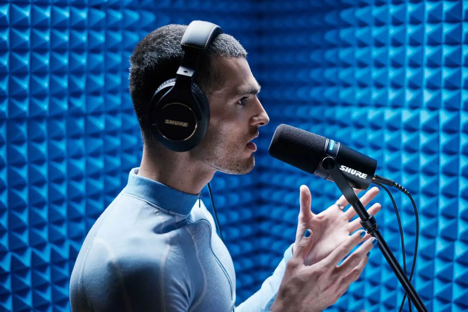 A podcaster speaking into a Shure MV7+ on a boom arm