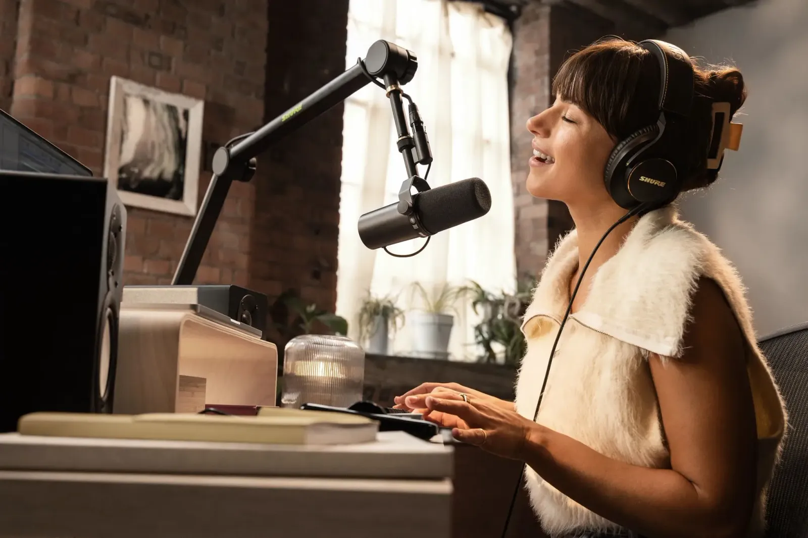 A podcaster at a desk speaking into a Shure SM7B on a boom arm