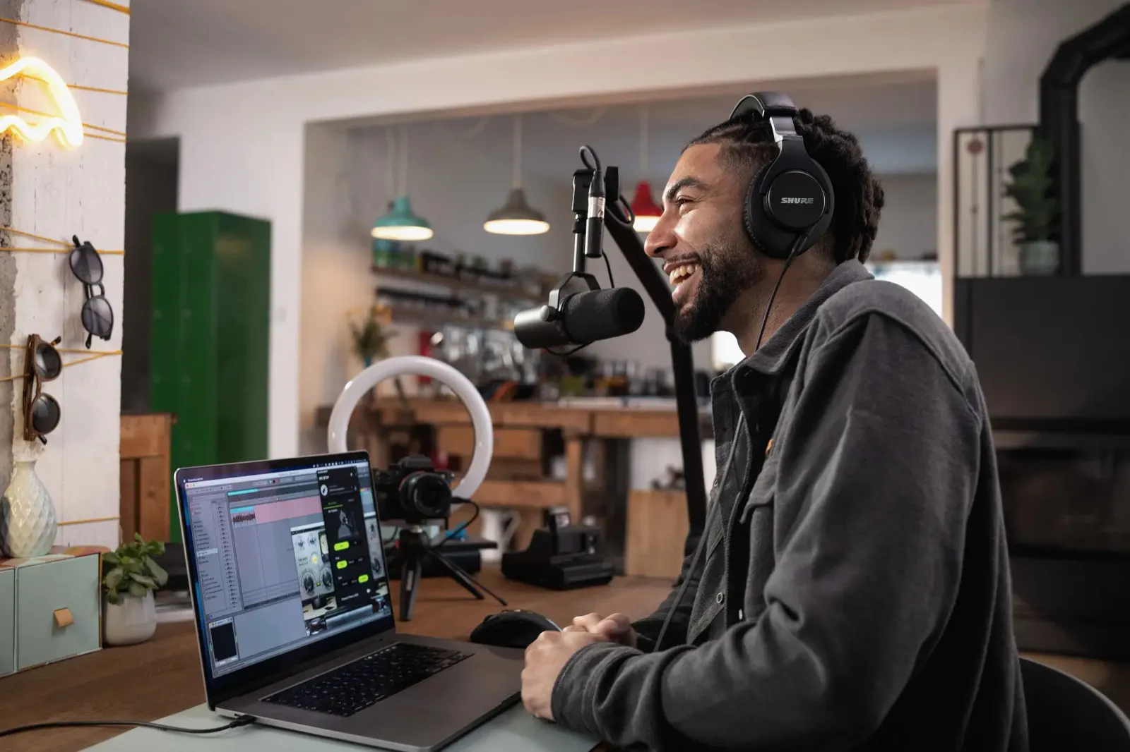 A podcaster with headphones and a laptop, using a Shure SM7B on a boom arm