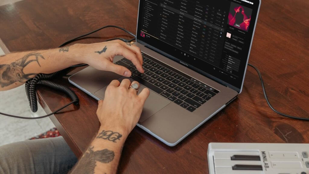 best computer for music production - man with tattoos using a MacBook pro